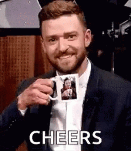 A Man In A Suit Is Holding A Coffee Mug With A Picture Of A Woman On It . GIF
