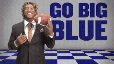 A Man In A Suit Is Holding A Football In Front Of The Words Go Big Blue GIF