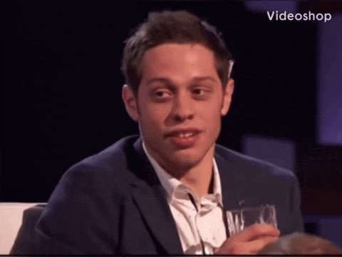 A Man In A Suit Is Holding A Glass And Making A Funny Face GIF