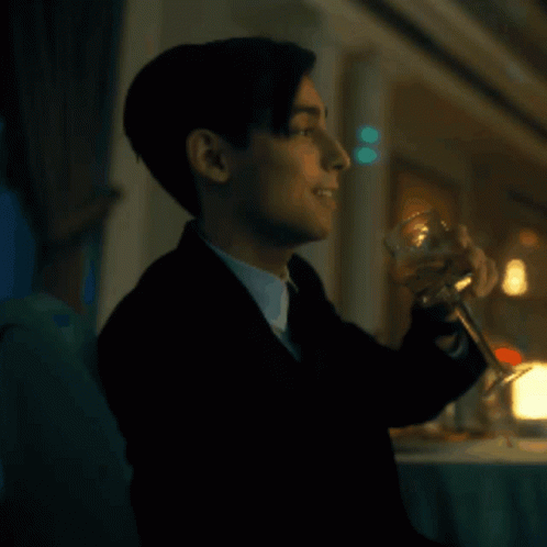 A Man In A Suit Is Holding A Glass Of Wine GIF