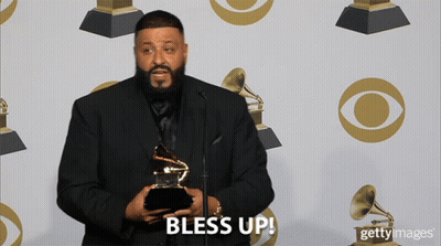A Man In A Suit Is Holding A Grammy Trophy And Says Bless Up GIF