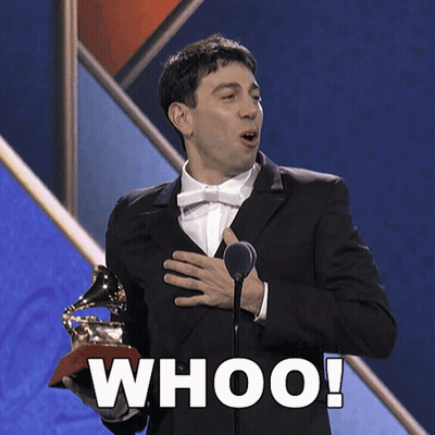 A Man In A Suit Is Holding A Grammy Trophy And Says Whoo GIF