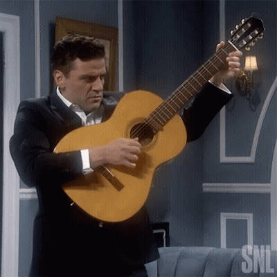 A Man In A Suit Is Holding A Guitar With The Snl Logo In The Corner GIF