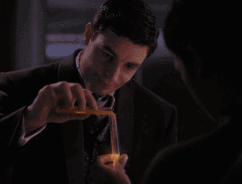 A Man In A Suit Is Holding A Lit Lighter GIF