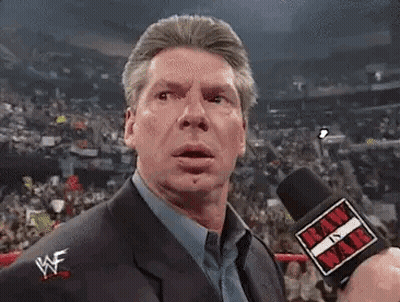 A Man In A Suit Is Holding A Microphone In Front Of A Crowd Of People . GIF