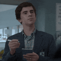 A Man In A Suit Is Holding A Pen And A Notepad GIF