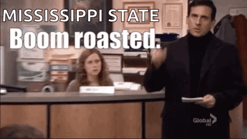 A Man In A Suit Is Holding A Piece Of Paper In Front Of A Woman At A Desk . GIF