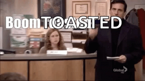 A Man In A Suit Is Holding A Piece Of Paper In Front Of A Woman At A Desk In An Office . GIF