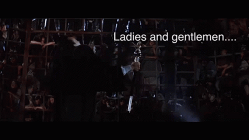 A Man In A Suit Is Holding A Trophy In His Hand And Saying `` Dyin ' Time 'S Here '' . GIF