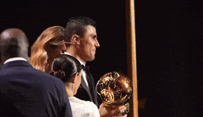 A Man In A Suit Is Holding A Trophy In His Hands GIF
