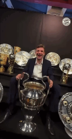A Man In A Suit Is Holding A Trophy In His Hands GIF