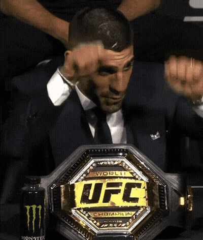 A Man In A Suit Is Holding A Ufc Belt GIF