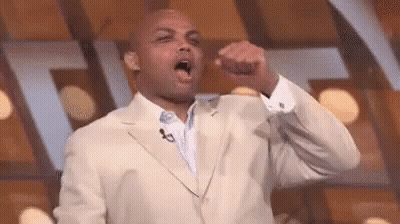 A Man In A Suit Is Holding His Fist Up In The Air . GIF