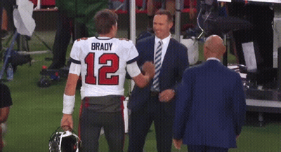 A Man In A Suit Is Hugging A Man In A Brady Jersey GIF
