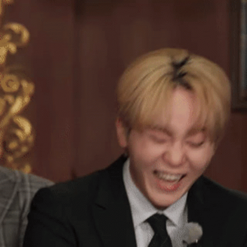 A Man In A Suit Is Laughing And Holding A Piece Of Paper GIF