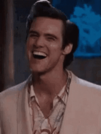A Man In A Suit Is Laughing And Looking At The Camera . GIF