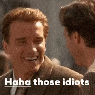 A Man In A Suit Is Laughing While Talking To Another Man In A Suit . GIF