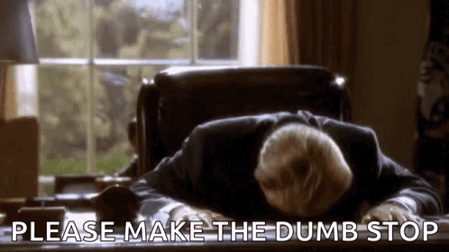 A Man In A Suit Is Laying On A Desk With His Head On His Desk . GIF