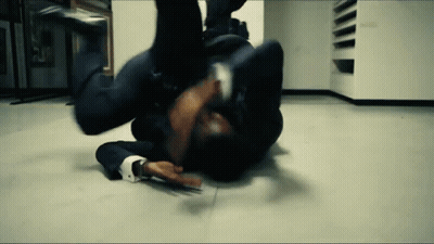A Man In A Suit Is Laying On The Floor In A Room . GIF