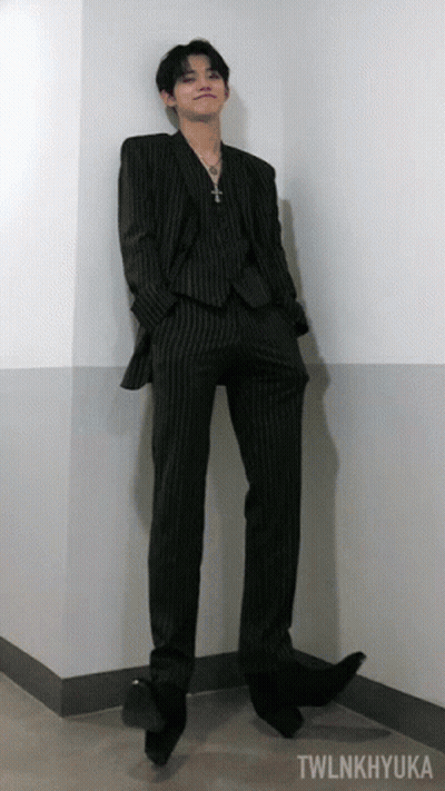 A Man In A Suit Is Leaning Against A Wall With Twlnkhyuka Written On The Bottom GIF