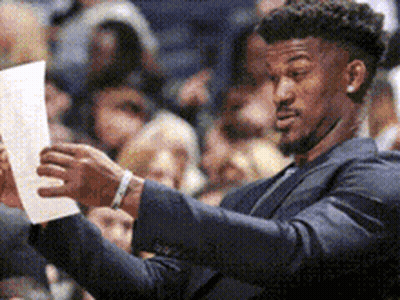 A Man In A Suit Is Looking At A Piece Of Paper . GIF