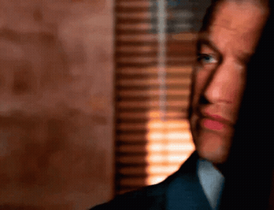 A Man In A Suit Is Looking Out A Window GIF
