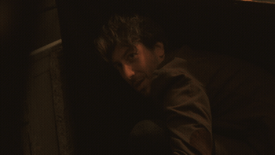 A Man In A Suit Is Looking Out From Behind A Wall GIF