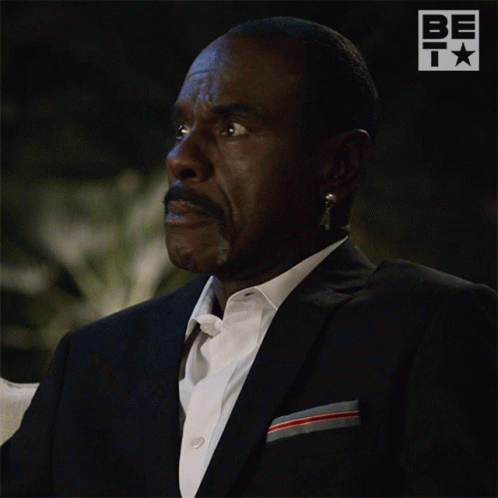 A Man In A Suit Is Looking Up With A Be T Logo In The Background GIF