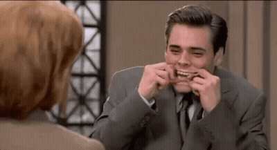 A Man In A Suit Is Making A Funny Face While Talking To A Woman . GIF