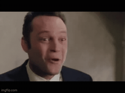 A Man In A Suit Is Making A Funny Face . GIF