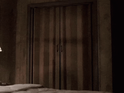 A Man In A Suit Is Peeking Out Of A Doorway GIF