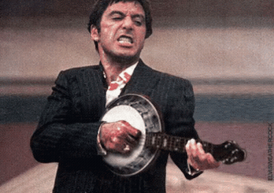 A Man In A Suit Is Playing A Banjo With Blood On His Shirt . GIF