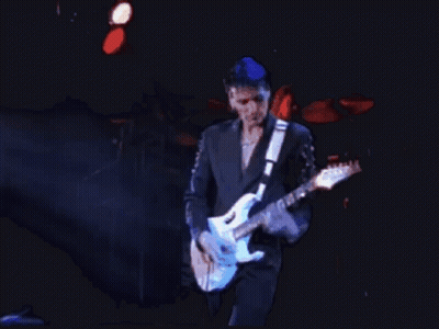 A Man In A Suit Is Playing A Blue Guitar GIF
