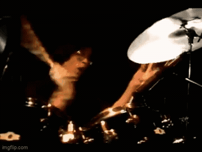 A Man In A Suit Is Playing A Guitar On Stage . GIF