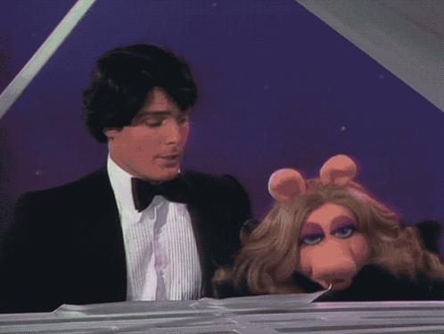 A Man In A Suit Is Playing A Piano Next To Miss Piggy GIF