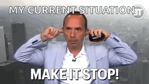 A Man In A Suit Is Plugging His Ears With His Fingers While Talking On A Cell Phone . GIF