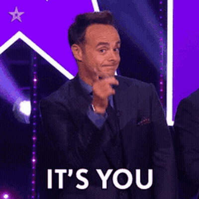 A Man In A Suit Is Pointing At The Camera With The Words It 'S You Behind Him GIF