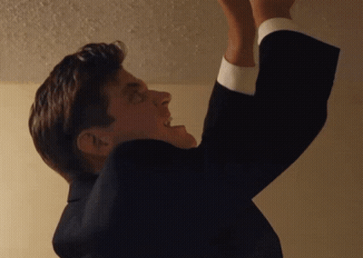 A Man In A Suit Is Reaching Up To Reach Something GIF