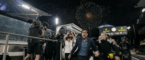 A Man In A Suit Is Running Towards A Rolex Sign GIF