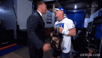 A Man In A Suit Is Shaking Hands With A Man In A White Shirt That Says ' Rapp Arena ' GIF