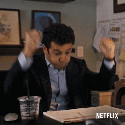 A Man In A Suit Is Sitting At A Desk With His Arms In The Air And A Netflix Logo On The Bottom GIF