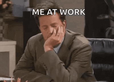 A Man In A Suit Is Sitting At A Desk With His Hand On His Chin And Says `` Me At Work '' . GIF