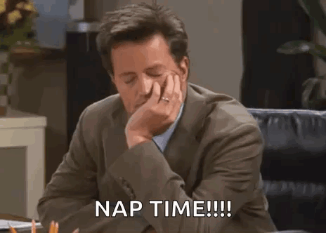 A Man In A Suit Is Sitting At A Desk With His Hand On His Face And The Words `` Nap Time '' . GIF