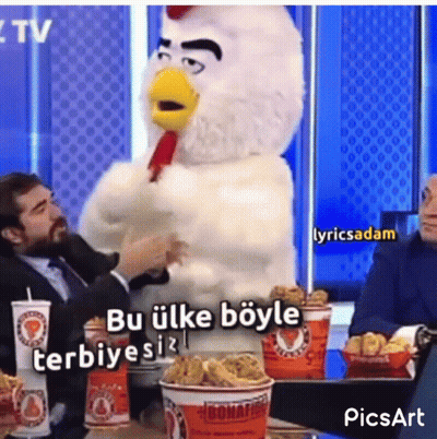 A Man In A Suit Is Sitting At A Table With A Chicken Mascot Standing Next To Him . GIF
