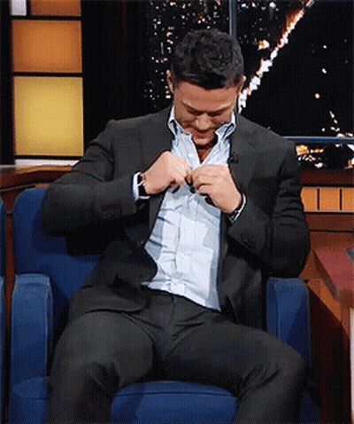 A Man In A Suit Is Sitting In A Chair GIF