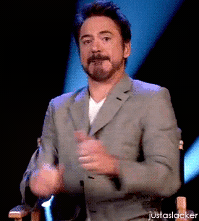 A Man In A Suit Is Sitting In A Chair With His Hands In The Air And The Words Justaslacker Below Him GIF