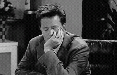 A Man In A Suit Is Sitting In A Chair With His Head Resting On His Hand . GIF