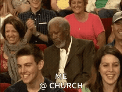 A Man In A Suit Is Sitting In A Crowd Of People Applauding And Laughing . GIF