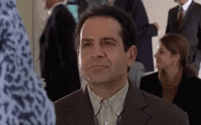 A Man In A Suit Is Sitting In A Crowd Of People GIF