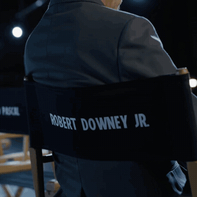A Man In A Suit Is Sitting In A Director 'S Chair With Pedro Pascal Written On The Back GIF